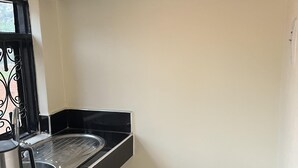 A compact kitchen with a sink, a kettle, and a gas stove.