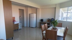 Eine moderne Küche mit Essbereich, inklusive Kühlschrank, Herd und einem Esstisch mit Stühlen.