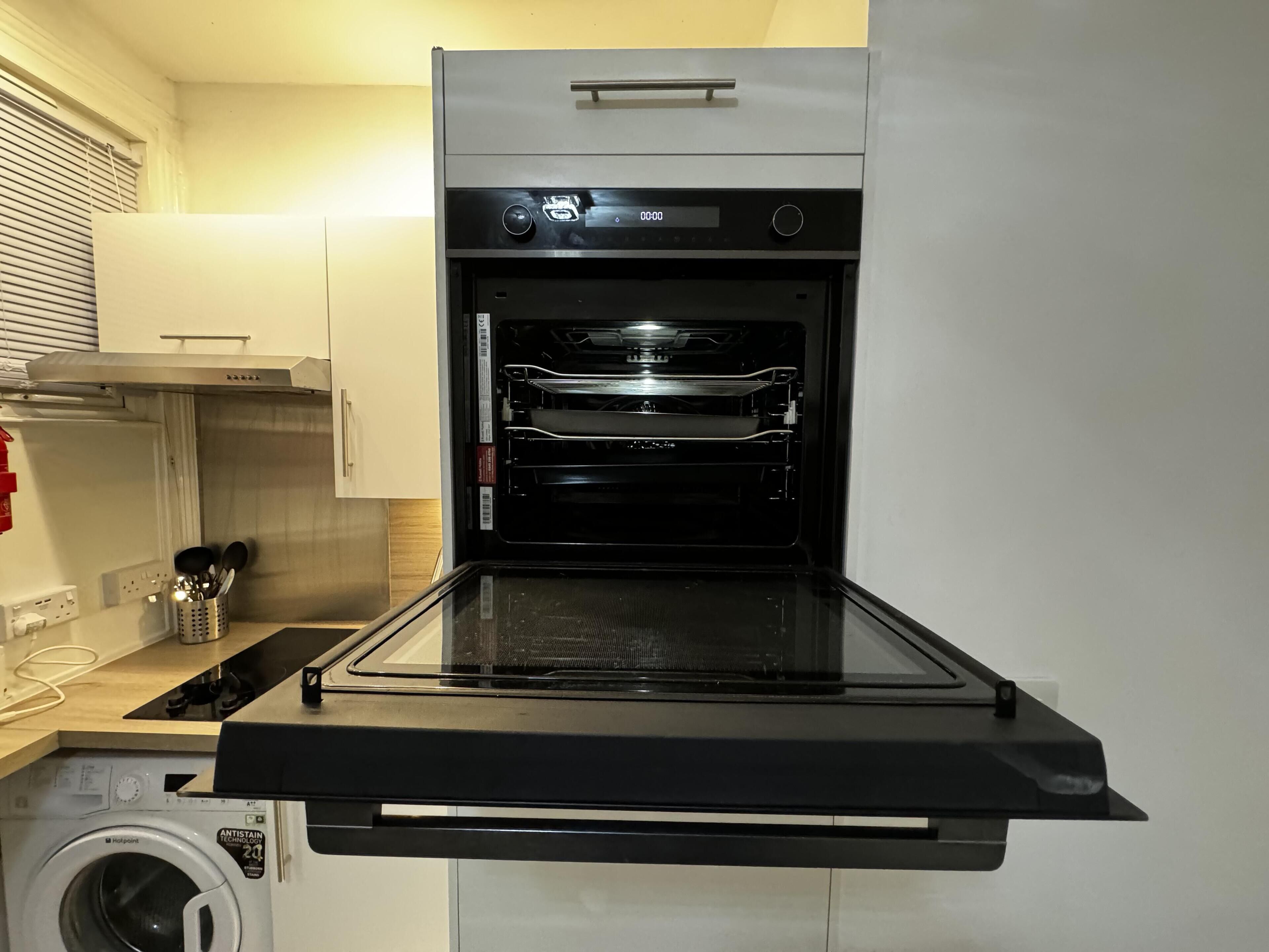 Una cocina compacta con horno integrado, lavadora y microondas.