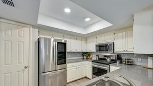 A modern kitchen with white cabinets, stainless steel appliances, and a skylight. - Y'all Stay Here Inn (Austin)