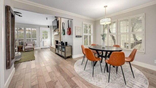 A dining area with a round table and orange chairs, a kitchen with a built-in oven, and a staircase with white shutters. - Y'all Stay Here Inn (Austin)