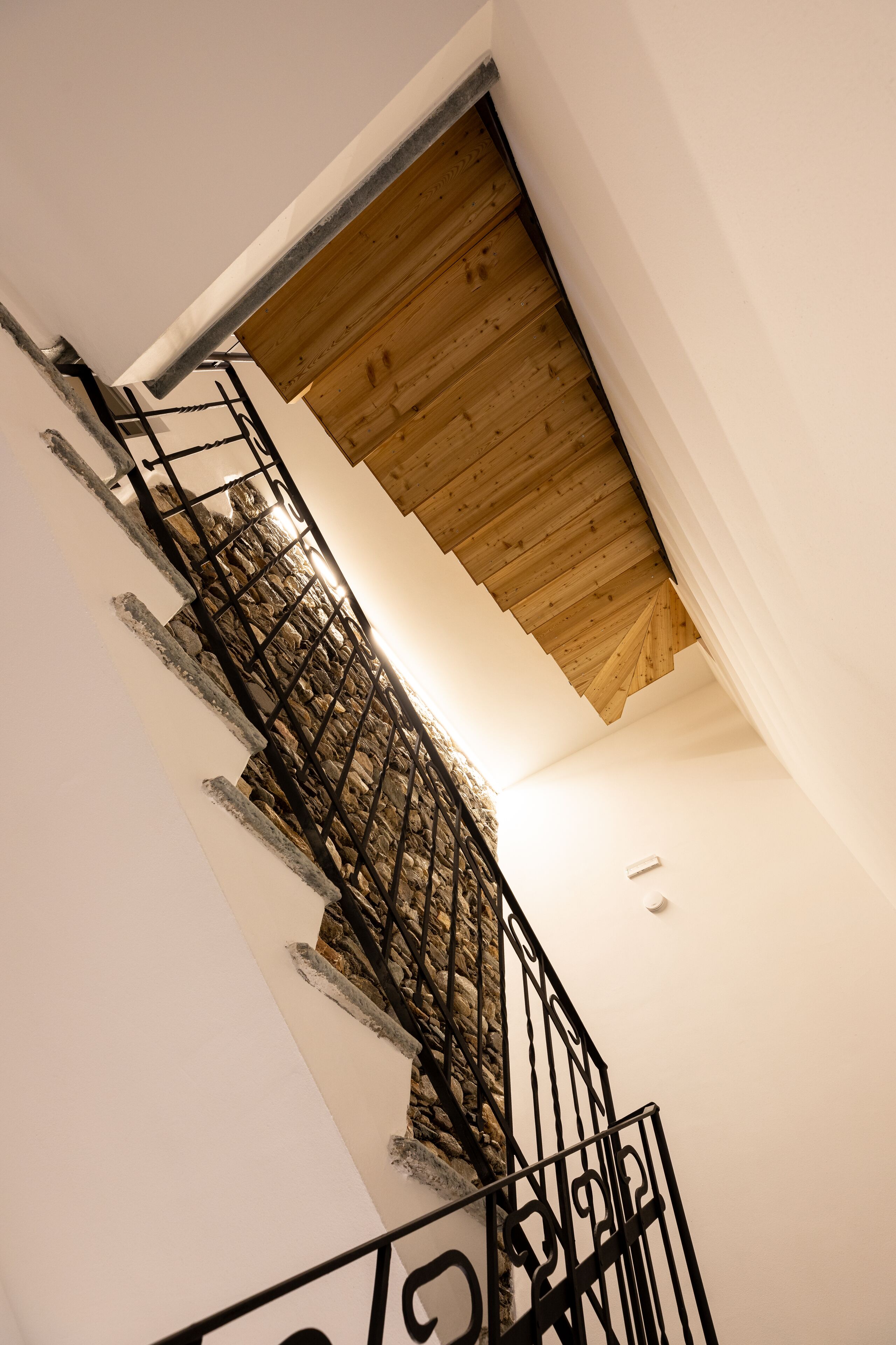 Una escalera con techo de madera y paredes blancas.