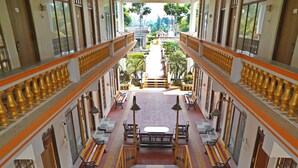 A multi-level interior with a central staircase, railings, and benches. - Icon Heritage Bakkhali - Where the Sea Meets Luxury (Kakdwip)