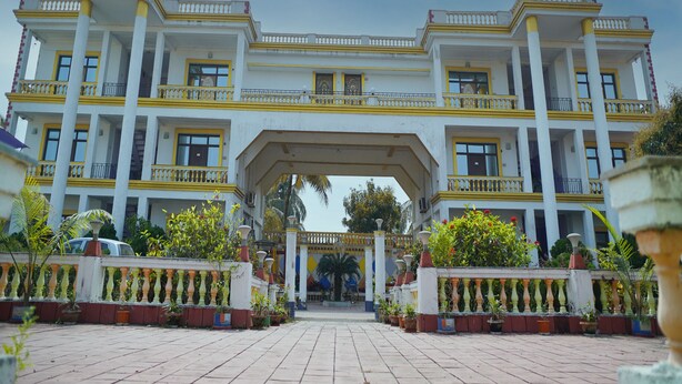 A large, multi-story building with a symmetrical facade, multiple balconies, and a central entrance with a canopy. - Icon Heritage Bakkhali - Where the Sea Meets Luxury (Kakdwip)