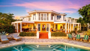 Uma casa de dois andares com piscina, área de estar externa e um jardim bem cuidado.