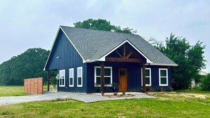 A single-story house with a dark blue exterior, a sloped roof, and a front porch with two chairs.