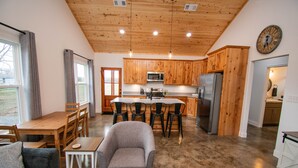 A modern kitchen with wooden cabinets, a central island, and a dining area with a sofa and chairs.