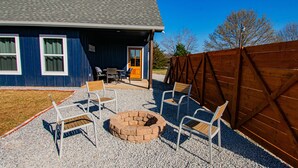 A house with a blue exterior, a gravel patio, and a fire pit.