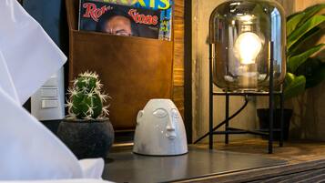 Ein Zimmer mit einer Holzvertäfelung, einem Zeitschriftenständer mit der Zeitschrift 'AXIS', einem Kaktus, einer Lampe und einer kleinen weißen Skulptur.