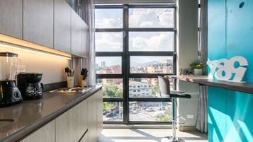 Una cocina moderna con un ventanal grande, una cafetera y un taburete de bar.