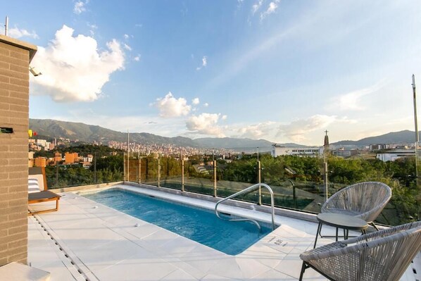 A rooftop swimming pool with a clear view of a cityscape and mountains in the background. - Factory Lofts (MedellÃn)