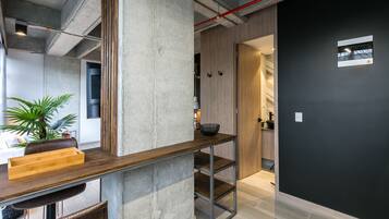 A modern interior with a concrete pillar, a wooden table, and a black wall.
