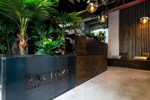 Welcome to the reception area, featuring a stylish desk with engraved details, lush greenery, and modern pendant lighting.