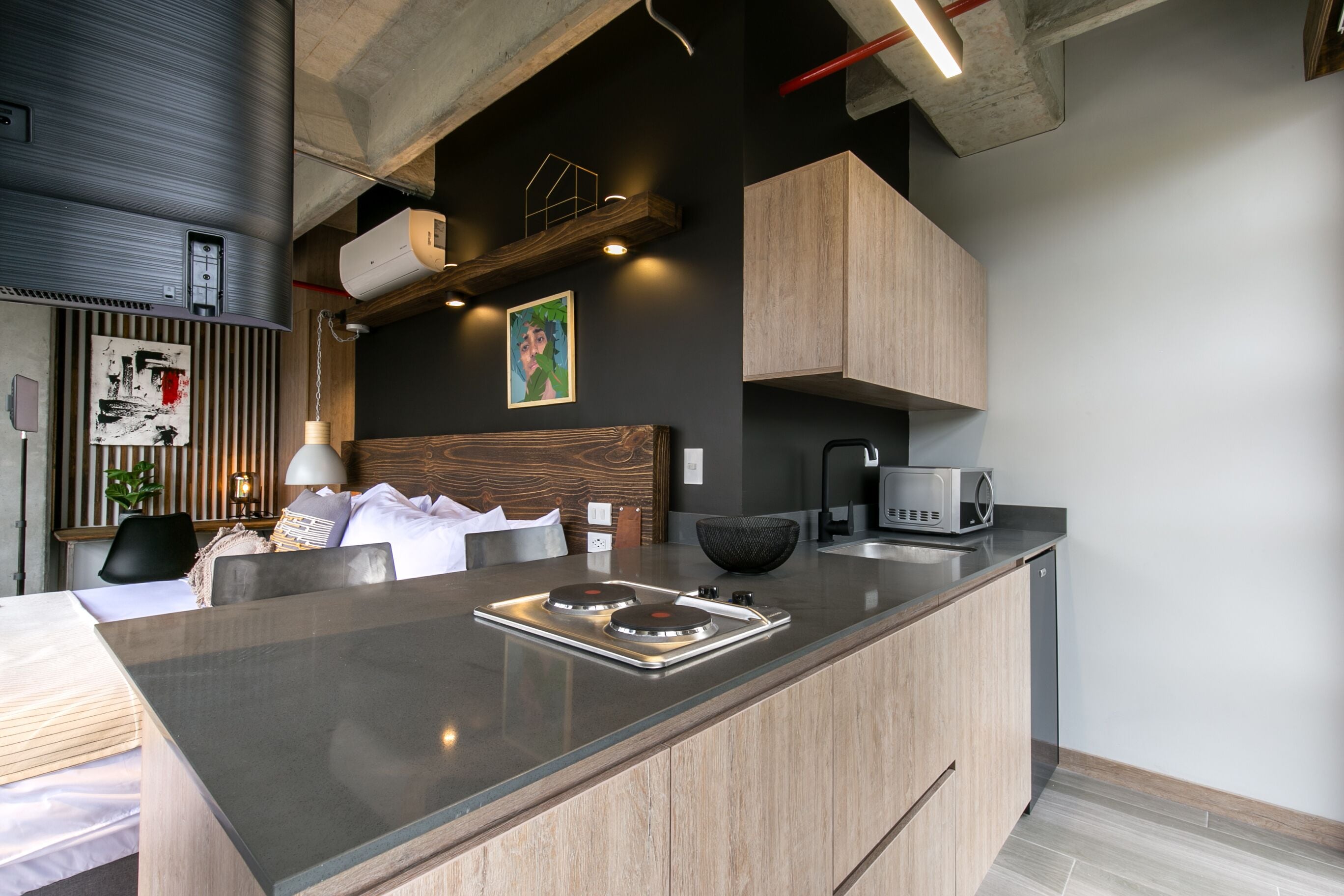 A modern kitchen with a central island, built-in appliances, and a dining area with a wooden headboard.