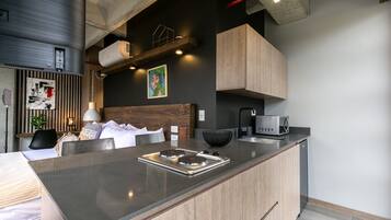A modern kitchen with a central island, built-in appliances, and a dining area with a wooden headboard.