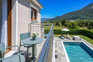 Un balcón con piscina, sillas y una mesa con planta en maceta.