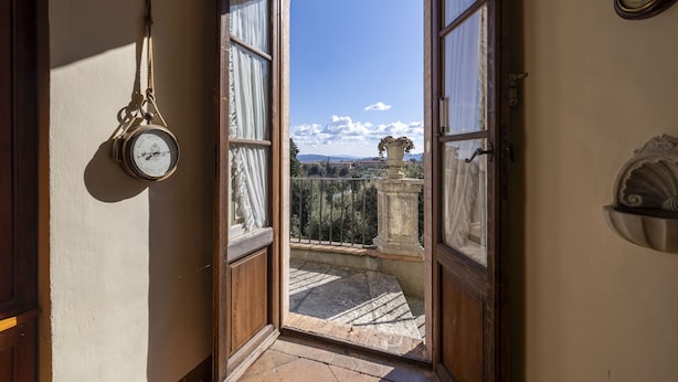 A corridor with a view of a balcony and a clock on the wall. - CASTELLO DI SOVICILLE- RESIDENZA D'EPOCA (Sovicille)