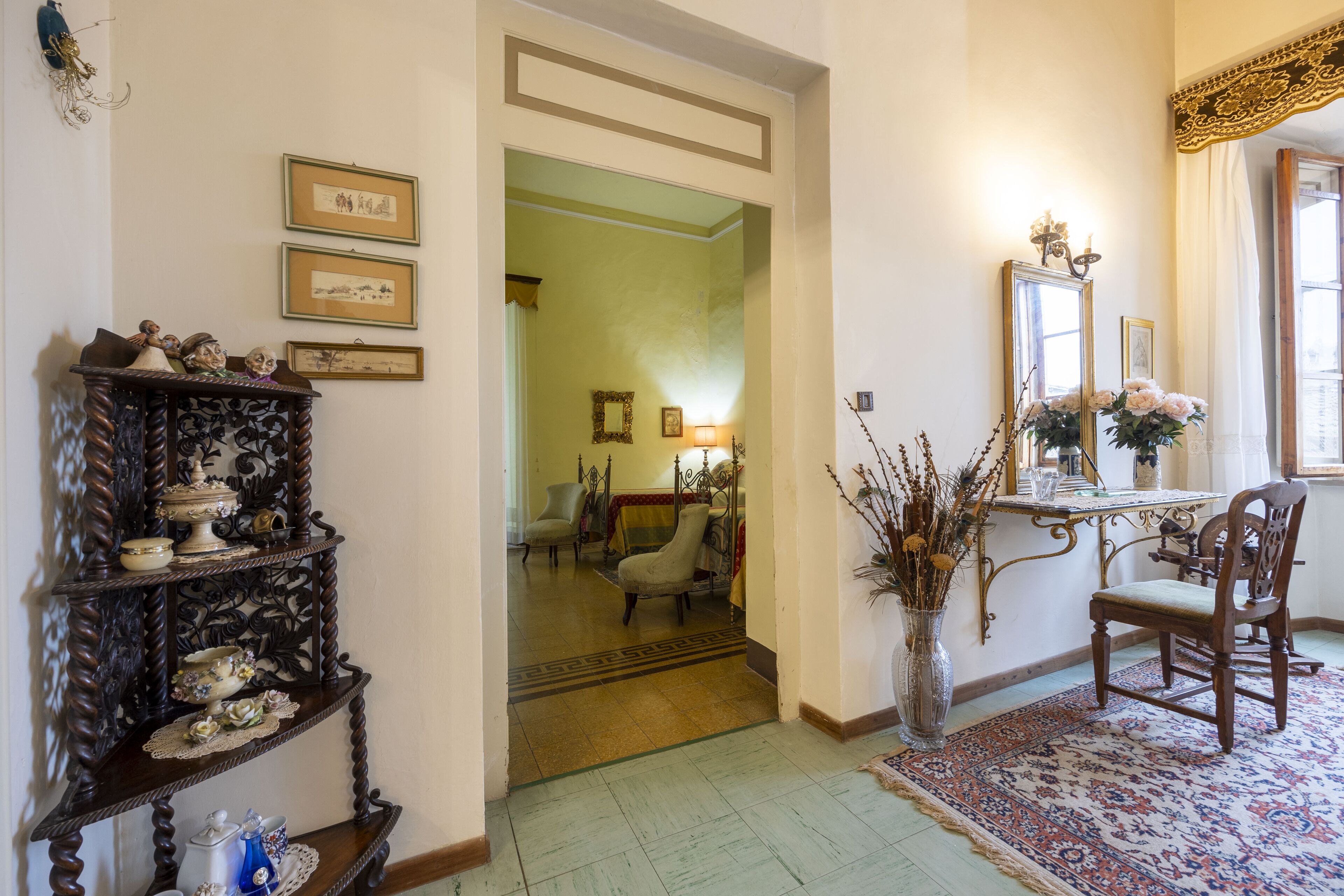 A traditional interior with a wooden chair, a table with a vase, and a mirror on the wall.