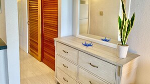 A hallway with a wooden door, a mirror, a dresser, and a potted plant. - Beachfront Condo in Christiansted with Ocean View (Christiansted)