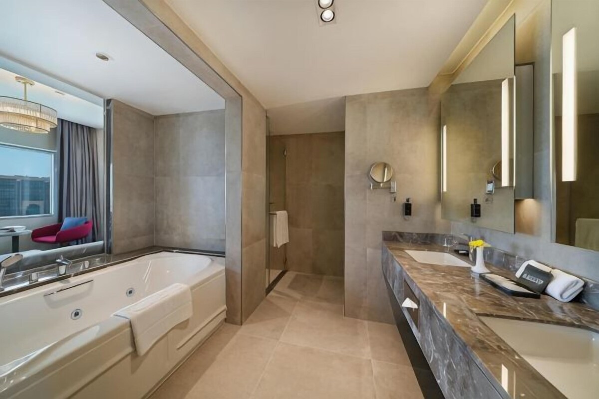 A modern bathroom with a large bathtub, a vanity with a mirror, and a shower area.