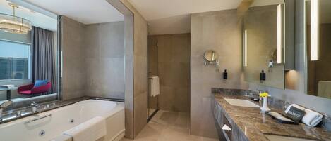 A modern bathroom with a large bathtub, two sinks, and a vanity area.