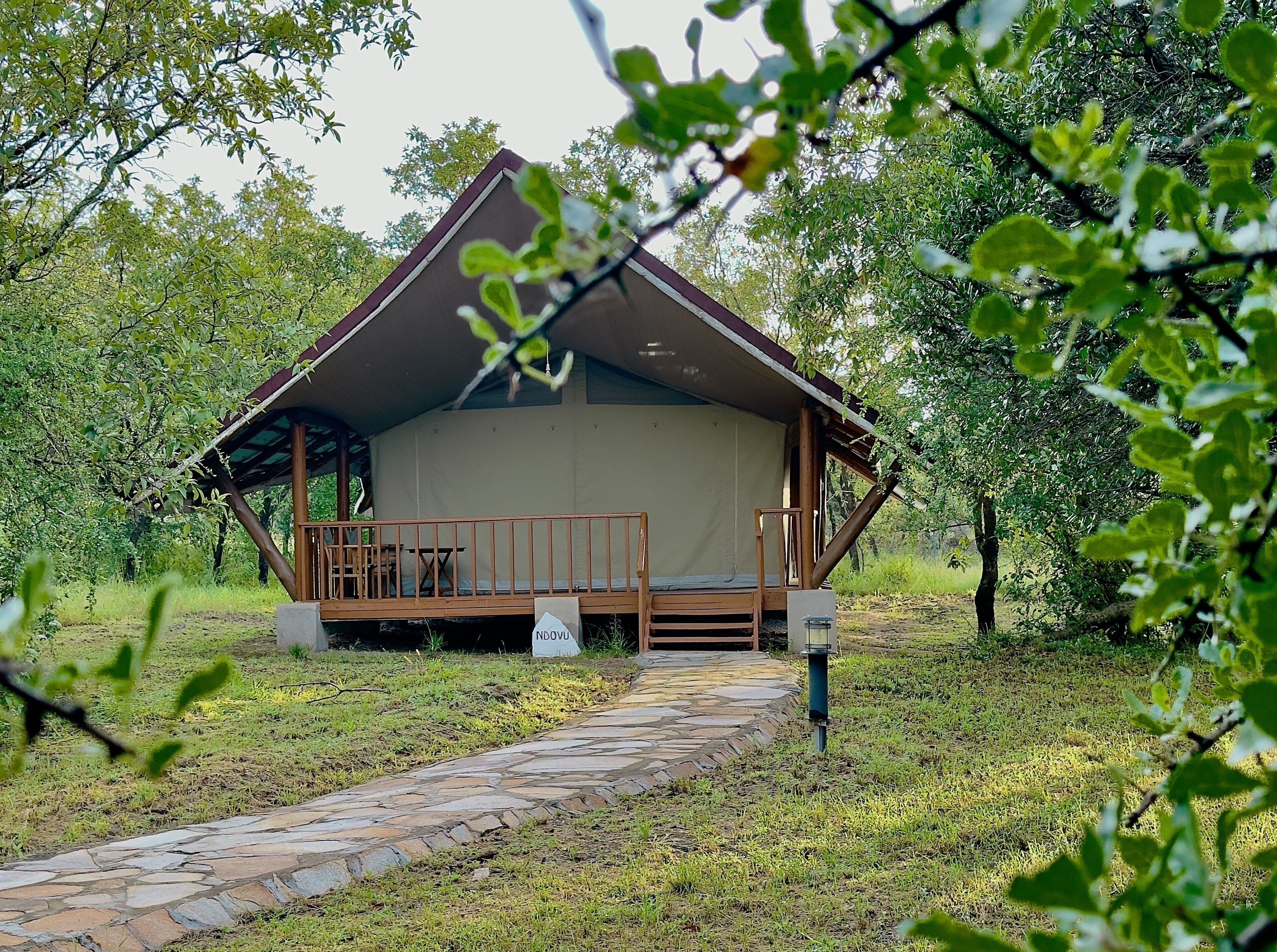 A small, single-story cabin with a porch and a stone pathway leading to it.