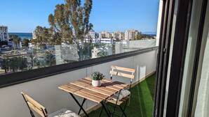 En balkon med et træbord, to stole og en potteplante.