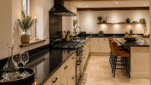 Una cocina moderna con una isla central, taburetes de bar, estufa y una campana extractora negra.