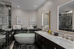 A modern bathroom with a freestanding bathtub, dual sinks, and marble flooring.