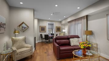 Una sala de estar moderna con un sofá de cuero, un sillón estampado y una mesa de centro de vidrio.