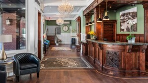 Un vestíbulo espacioso con un mostrador de recepción de madera, un candelabro y un espejo grande.