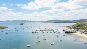 A marina with numerous boats docked, surrounded by hills and a clear sky.