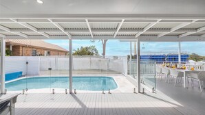 A covered outdoor swimming pool area with a view of a construction site in the background.