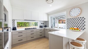 A modern kitchen with white cabinets, a built-in stove, and a large window.