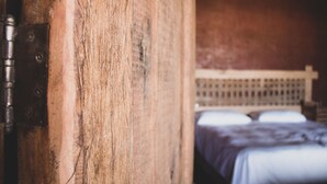 Una porta in legno con una chiusura metallica, un letto con testiera e un muro con motivo decorativo.