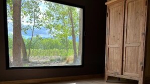Una stanza con un'ampia finestra, pavimento in legno e un armadio in legno.