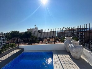 Une piscine sur le toit offrant une vue dégagée sur les bâtiments et un ciel ensoleillé.