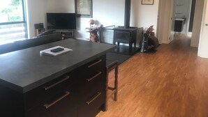 Une cuisine moderne avec un îlot central, une cuisinière noire et un téléviseur posé sur un meuble.