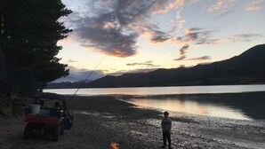 Une personne se tient sur une plage, près d’un véhicule et d’un feu de camp.