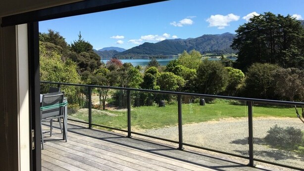 Un balcon avec vue sur un lac, des montagnes et la verdure.