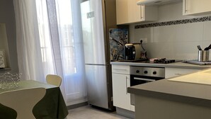 A modern kitchen with a refrigerator, stove, and dining area.
