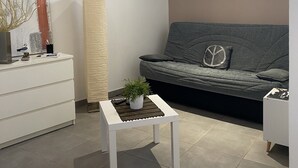 A modern living room with a grey sofa, a white coffee table with a plant, a tall floor lamp, and a painting on the wall.