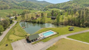 An aerial view of a rural area with a swimming pool, a small building, and a road.