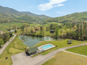 An aerial view of a rural area with a swimming pool, a small building, and a road. - Gettin Cozy - Peaceful Mountain Escape for Couples - Hot Tub, Pet Friendly (Sevierville)