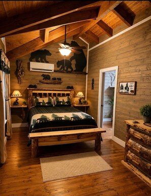 Une chambre confortable avec un lit en bois, un ventilateur de plafond et une décoration murale sur le thème des ours.