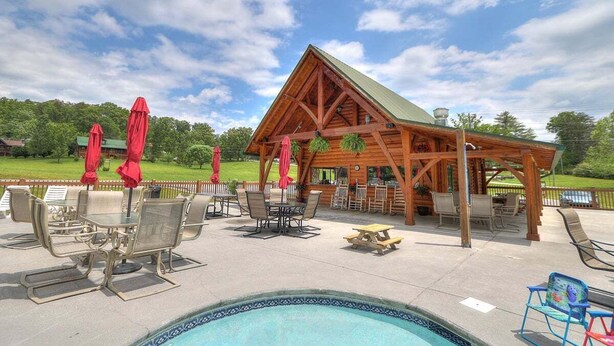 A wooden gazebo with a pool table and outdoor seating area.