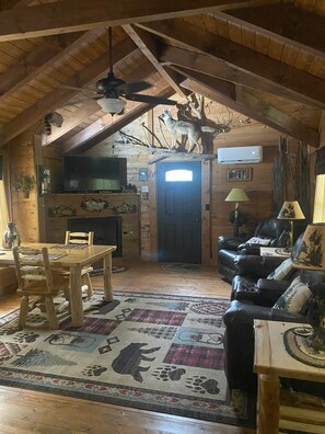 Ein rustikales Blockhaus-Interieur mit einem Holzesstisch, einer Ledersofa und einem Kamin.