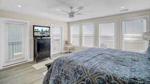 A bedroom with a bed, dresser, TV, and windows. - 131 Grand Pavilion by Avantstay Oceanfront On The Boardwalk! (Isle of Palms)