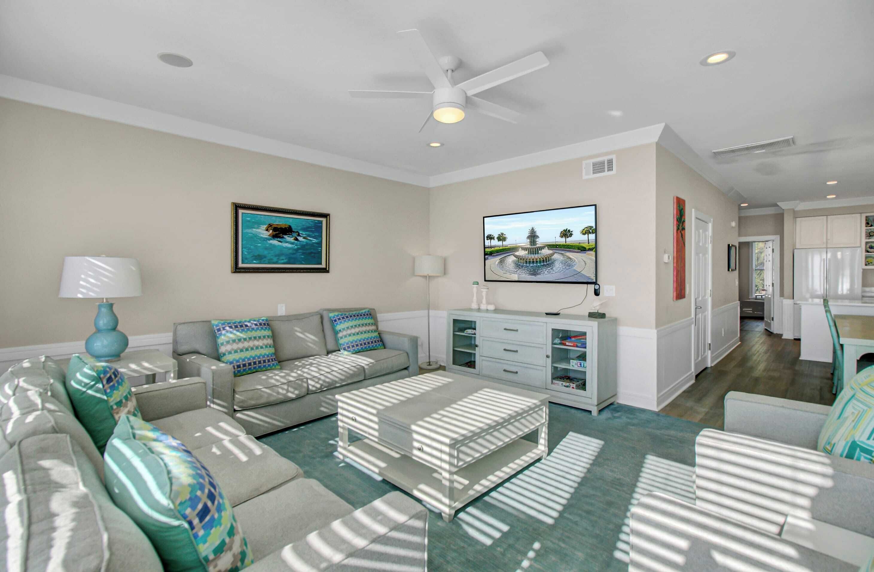 A living room with a sofa, coffee table, TV, and a ceiling fan.