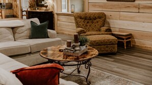 A cozy living room with a beige sofa, patterned armchair, and a round coffee table with decorative items.